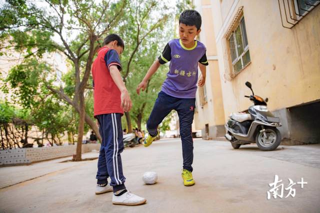 放学后，艾力和小伙伴一起在居住小区的楼下踢自己做的纸足球。